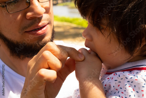 portrait of a Hispanic father and baby in a park smiling and having fun