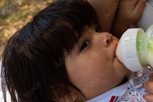 young Hispanic mother feeding her baby with a bottle