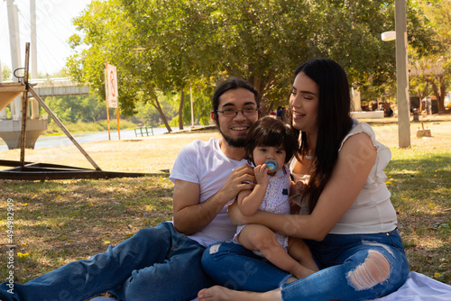 Young Hispanic parents playing with their one year old baby in a park