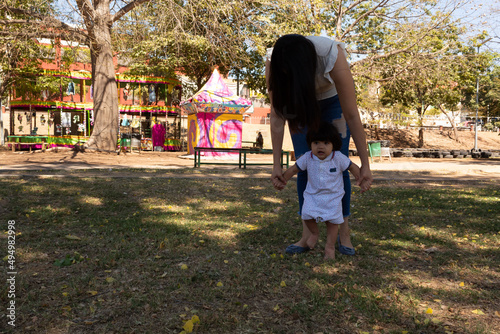 Young Hispanic mother playing with her one year old baby in a park
