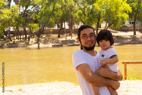 portrait of a Hispanic father and baby in a park smiling and having fun