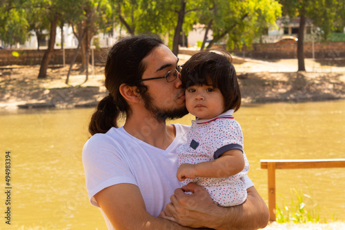 portrait of a Hispanic father and baby in a park smiling and having fun