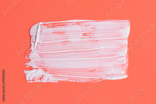 Abstract smear of white cosmetic cream on the orange background,abstract form.