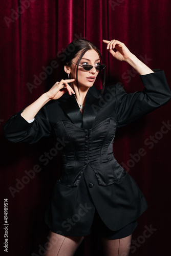 A model wearing all black posing in front of a red cinema curtain © Josep