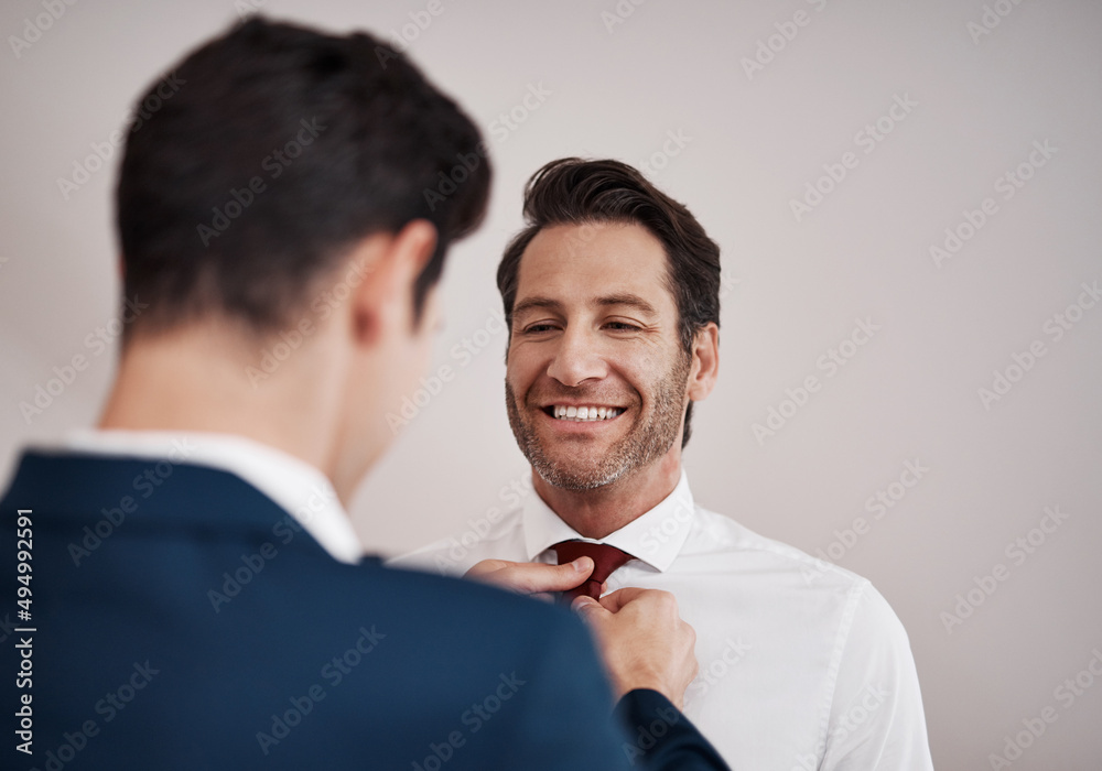 Gotta make sure the groom looks his best. Cropped shot of a young best man adjusting the grooms tie in a dressing room on the wedding day. Gotta make sure the groom looks his best. Cropped shot of a young best man adjusting the grooms tie in a dressing room on the wedding day.