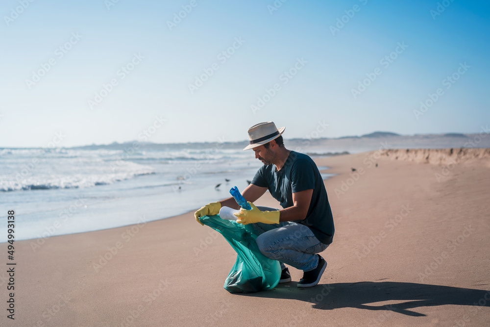 volunteer man collects plastic waste on the beach