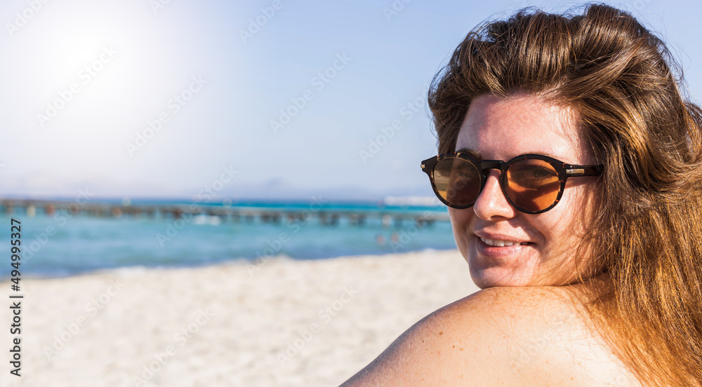 Close-up view of a redhead woman waring sun glasses on a paradise beach. Close-up view of a redhead woman waring sun glasses on a paradise beach.