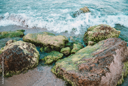 Closeup shot of foam waves hitting a rocky seashore