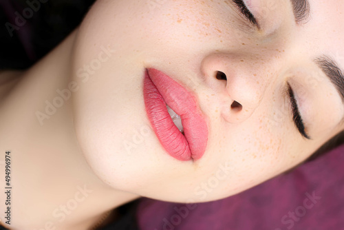 beautiful girl model with perfect permanent makeup on red lips