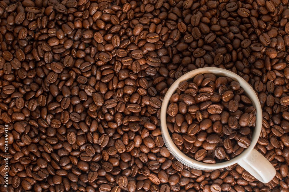 Many coffee beans in a traditional cup and at background Many coffee beans in a traditional cup and at background
