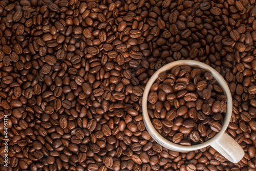 Many coffee beans in a traditional cup and at background 