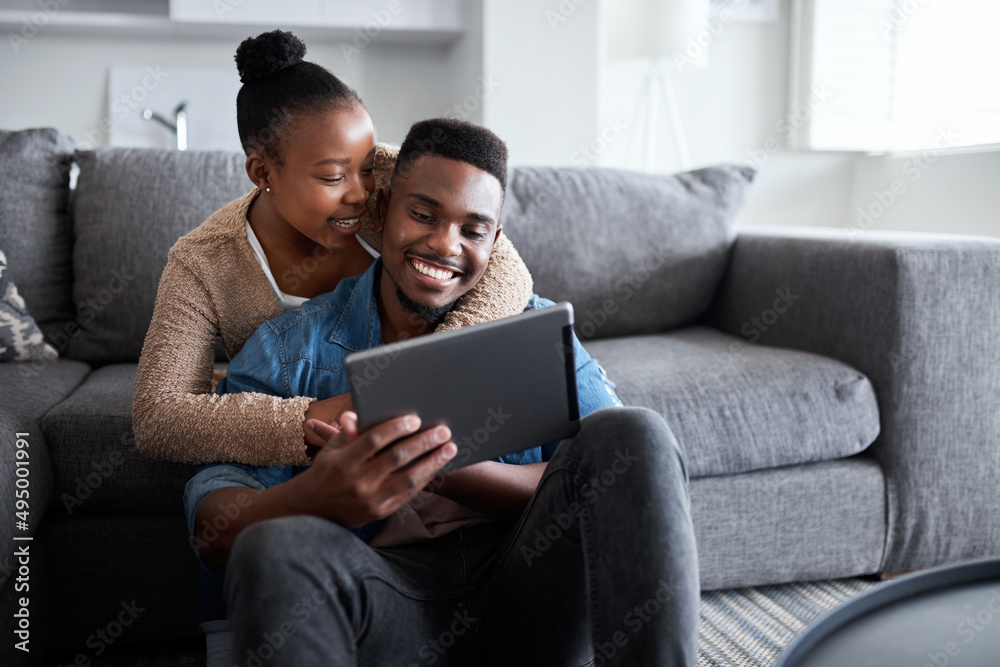 Sharing in a very special connection. Shot of a young couple using a digital tablet together while relaxing at home. Sharing in a very special connection. Shot of a young couple using a digital tablet together while relaxing at home.