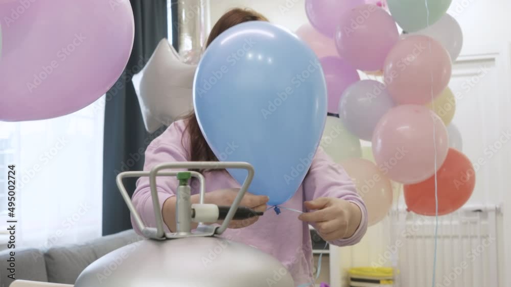 Woman using helium tank blowing up balloons to decorate home for party, colorful balloons for birthday wedding christmas party event decorations. High quality 4k footage