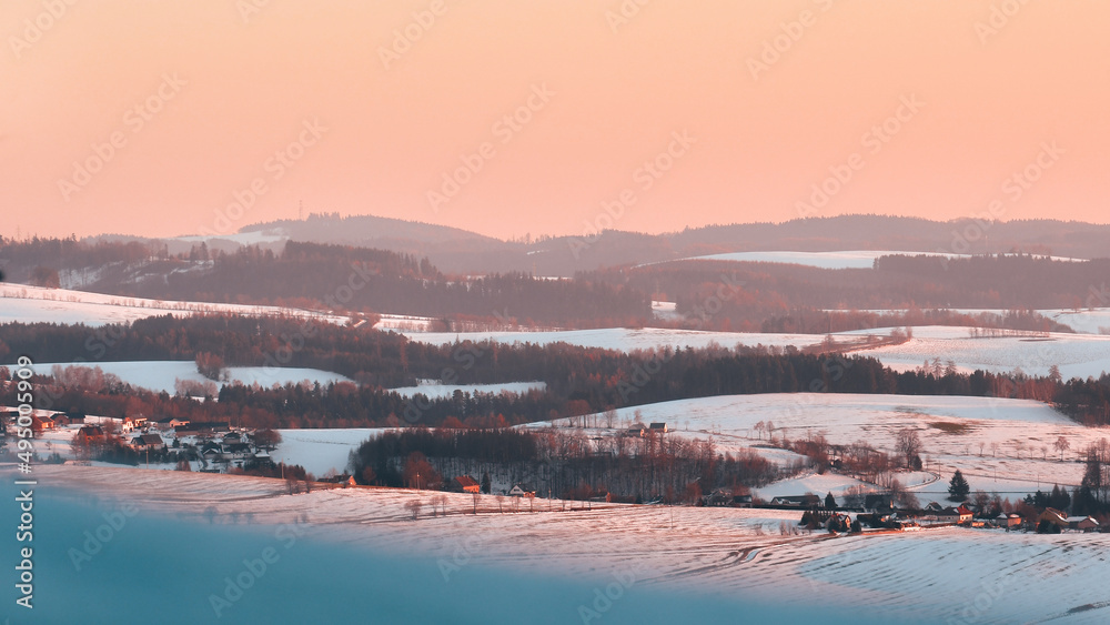 Studenecke Skaly, winter landscape in the mountains, snow-capped hills, view from the hiking trail at sunset.