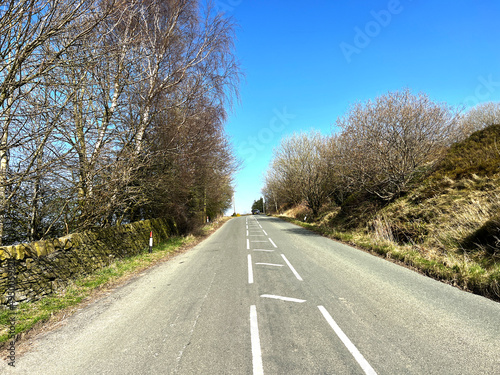 Late winter on, Brow Top Road, with bare trees, and a blue sky in, Haworth, UK