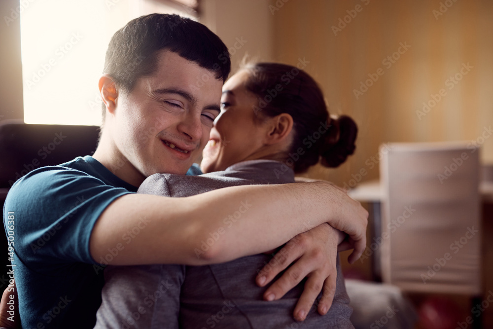 Happy man with down syndrome and his psychologist embrace while greeting at home.
