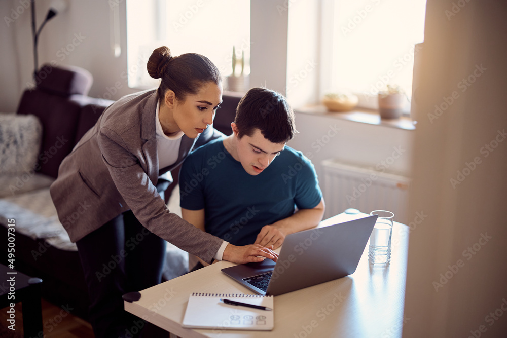 Special education teacher and man with down syndrome using laptop together. Special education teacher and man with down syndrome using laptop together.