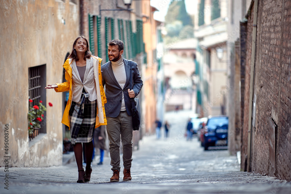 A young satisfied couple is walking the old city and chatting. Walk, rain, city, relationship