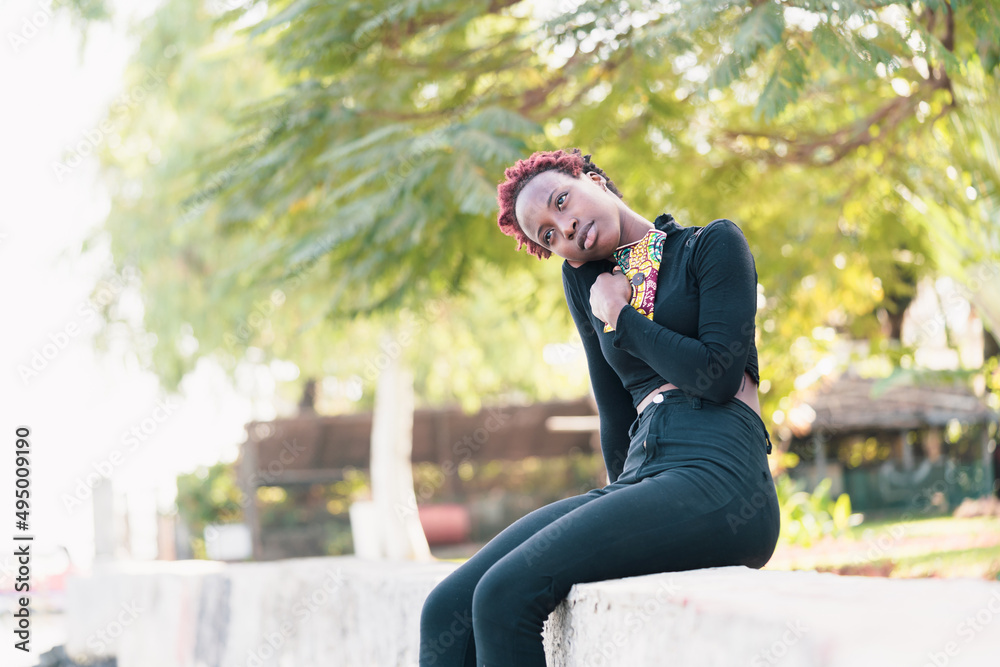 Melancholic African Girl sitting in a park, feeling nostalgic, recalling memories of her homeland. Migration concept. Melancholic African Girl sitting in a park, feeling nostalgic, recalling memories of her homeland. Migration concept.
