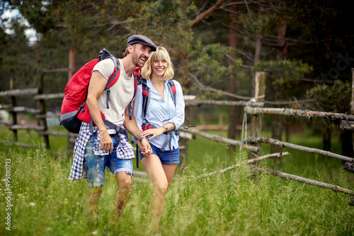  couple is hiking in mountain.Joyful man and woman at forest on sunny summer day