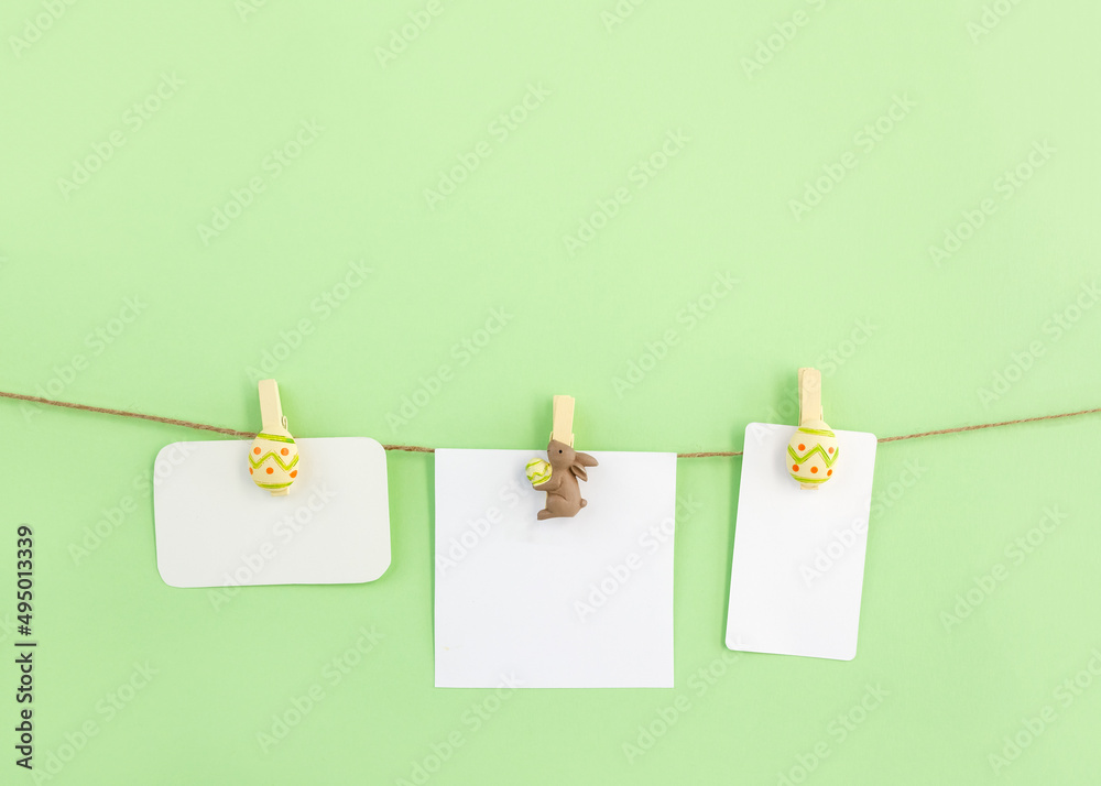 Wooden decorative clips in the shape of rabbit and eggs hold blank postcards. Easter greeting card mockup. Copy space Wooden decorative clips in the shape of rabbit and eggs hold blank postcards. Easter greeting card mockup. Copy space