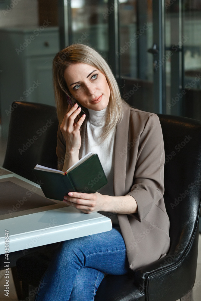 business beautiful self-confident woman sits at a table in a cafe waiting for an order and decides her working moments on the phone business beautiful self-confident woman sits at a table in a cafe waiting for an order and decides her working moments on the phone