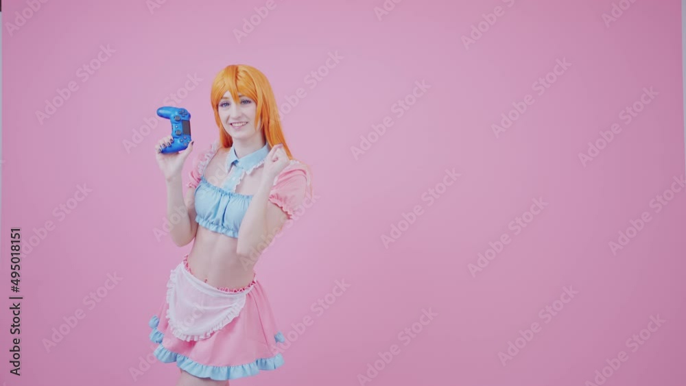 ginger-haired European girl in a cafeteria uniform is happy and satisfied because she won her first game using gamepad isolated pink background studio medium long shot. High quality 4k footage ginger-haired European girl in a cafeteria uniform is happy and satisfied because she won her first game using gamepad isolated pink background studio medium long shot. High quality 4k footage