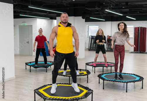 Women's and men's group on a sports trampoline, fitness training, healthy life - a concept trampoline group batut workout healthy, from female athletic in gym from teamwork person, smiling sportswear