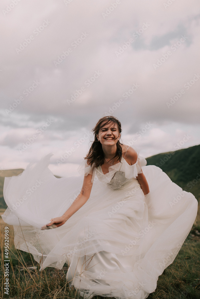 Happy bride in white wedding dress smiling against the backdrop of