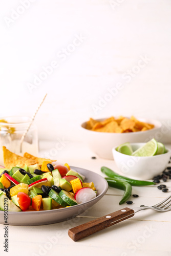 Bowl of delicious Mexican salad with black beans and radish on table