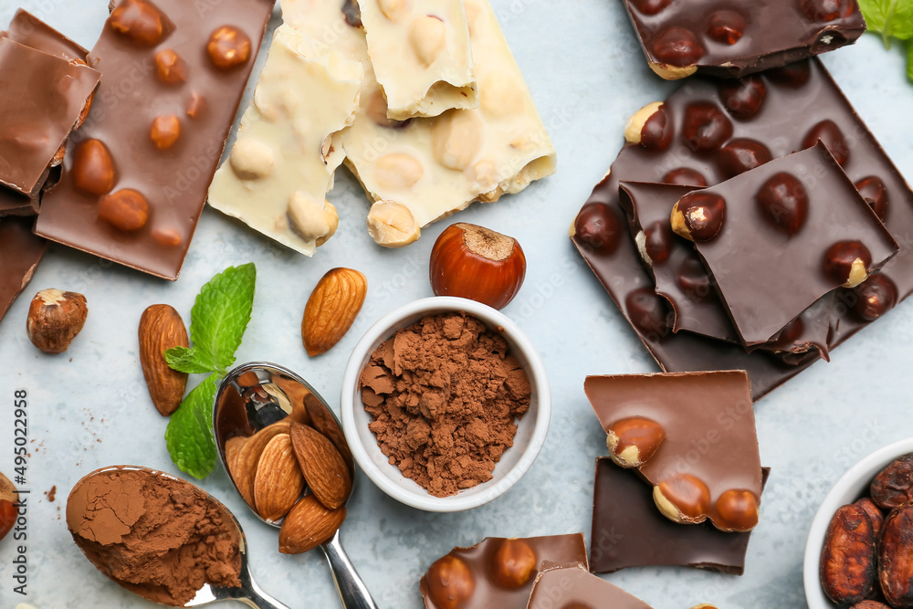 Pieces of tasty chocolate with nuts and cacao powder on color background Pieces of tasty chocolate with nuts and cacao powder on color background