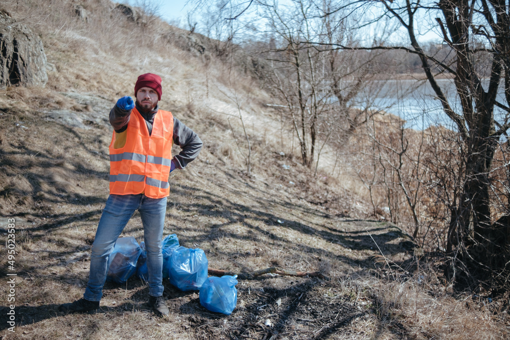 volunteer cleaner is cleaning up park and standing by bunch of garbage volunteer cleaner is cleaning up park and standing by bunch of garbage