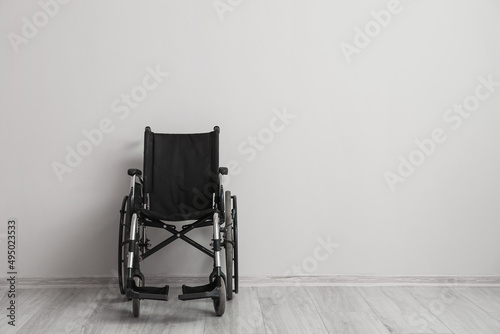 Empty wheelchair near light wall