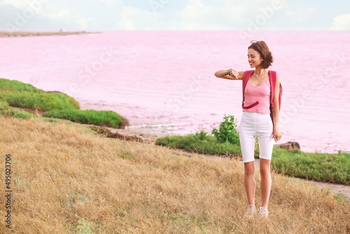 Young tourist looking at her fitness tracker near pink lake © Pixel-Shot