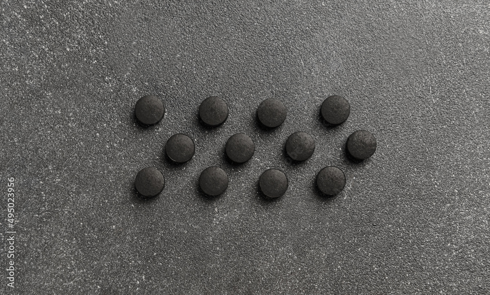 Activated carbon pills on dark background Activated carbon pills on dark background