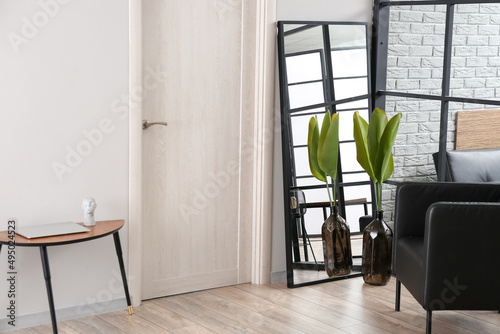 Interior of stylish room with armchair and mirror near light door © Pixel-Shot