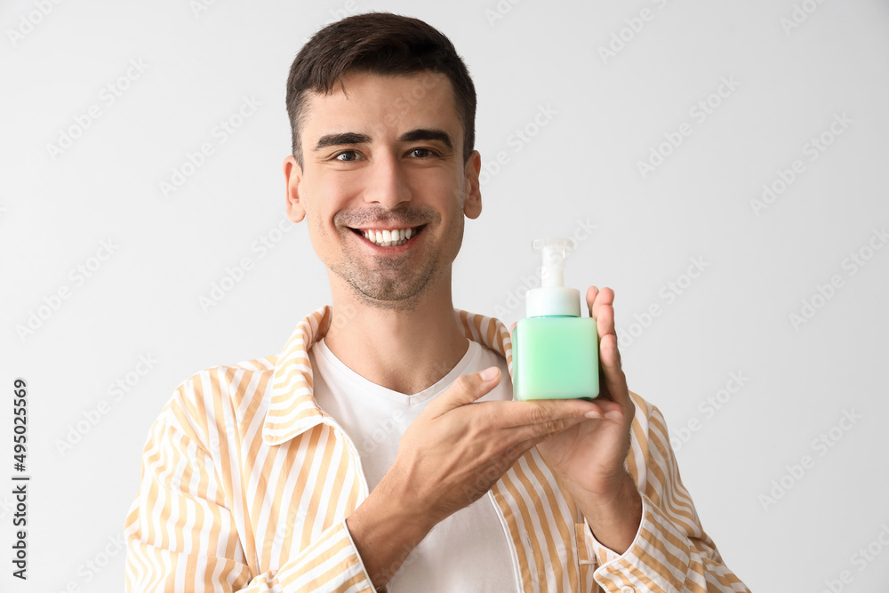 Handsome young man with liquid soap on light background Handsome young man with liquid soap on light background