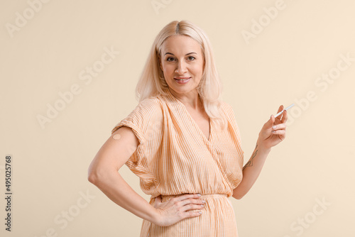 Mature woman with applied nicotine patch and cigarette on color background. Smoking cessation photo