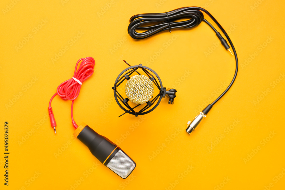 Modern microphones with stand and wires on orange background Modern microphones with stand and wires on orange background