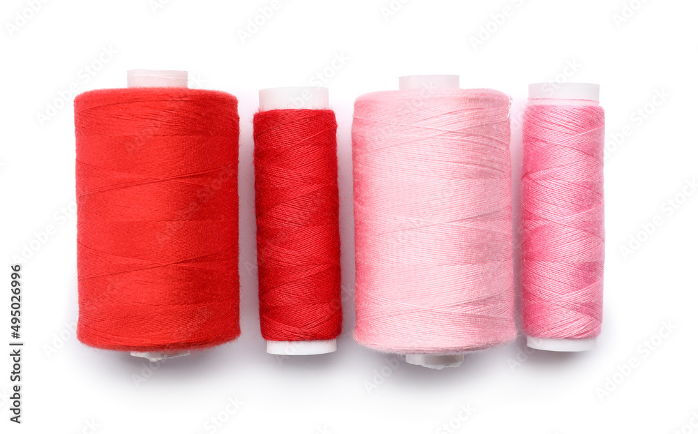Red and pink sewing thread spools on white background Red and pink sewing thread spools on white background