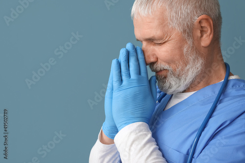Mature male doctor praying ...