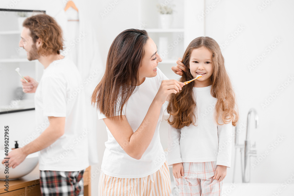 Young woman helping her little girl to brush teeth in bathroom Young woman helping her little girl to brush teeth in bathroom