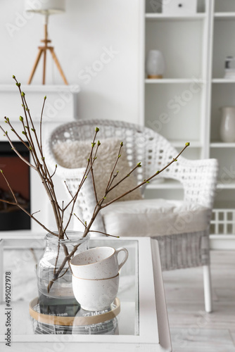 Home interior decor with spring branches and coffee cups on a glass table, co...