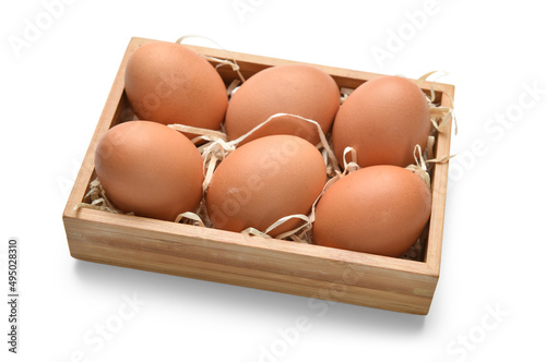 Wooden box with brown eggs on white background