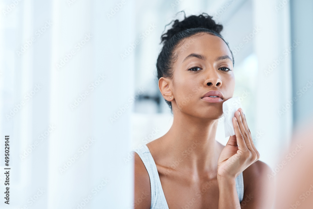 Shes serious about her skincare routine. Portrait of an attractive young woman cleaning her face with a cotton pad in the bathroom at home. Shes serious about her skincare routine. Portrait of an attractive young woman cleaning her face with a cotton pad in the bathroom at home.
