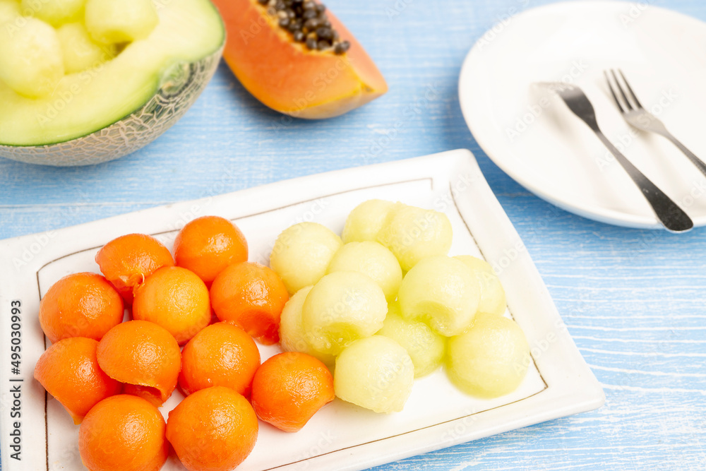 Organic Fresh Ripe Papaya, Thai tropical fruit and Fresh Japanese Melon cut in circle shapes serving on a white plate with blurred background of both types of fruits cut in pieces. Organic Fresh Ripe Papaya, Thai tropical fruit and Fresh Japanese Melon cut in circle shapes serving on a white plate with blurred background of both types of fruits cut in pieces.