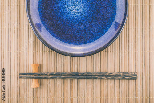 Empty Japanese plate dish and chopsticks on bamboo mat background. Japanese food, sushi, omakase concept.