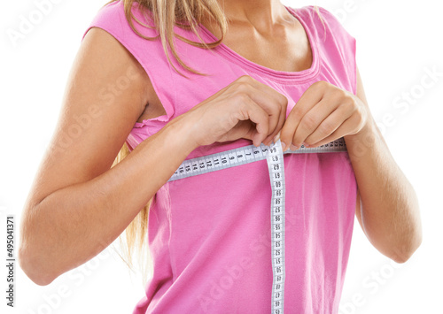 Keeping track of her curves. Cropped shot of a woman measuring her bust with a measuring tape against a white background.