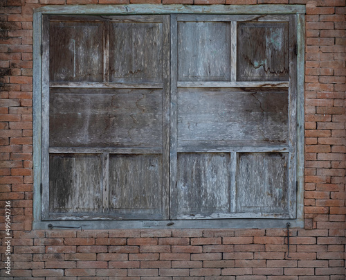 Weathered closed old wooden shutters on red brick background