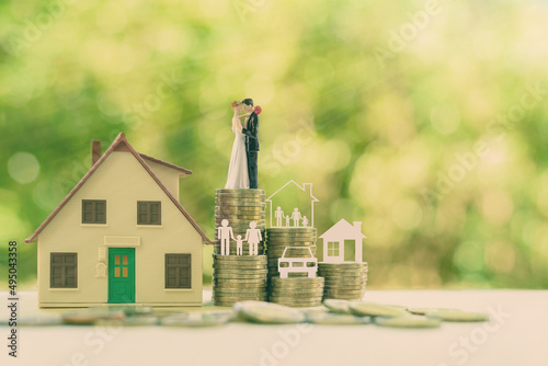 Sustainable financial goal for family life or married life concept : Miniature wedding couple, parent & child, a house or home, a car on rows of rising coins, depicts savings or growth for new family